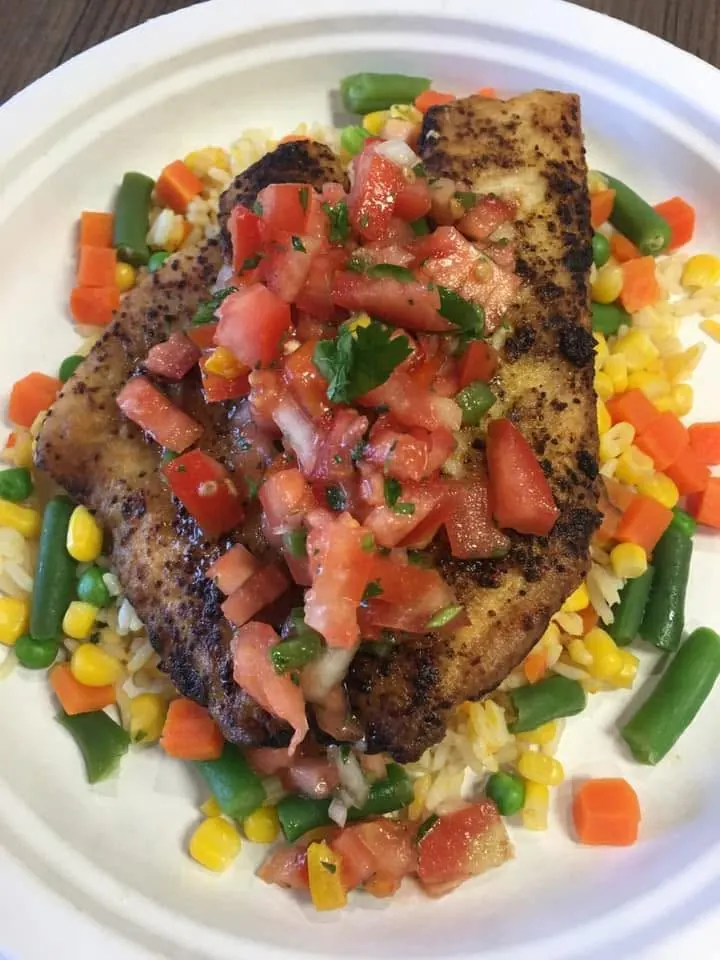 Blackened fish fillet topped with fresh pico de gallo over rice and mixed vegetables
